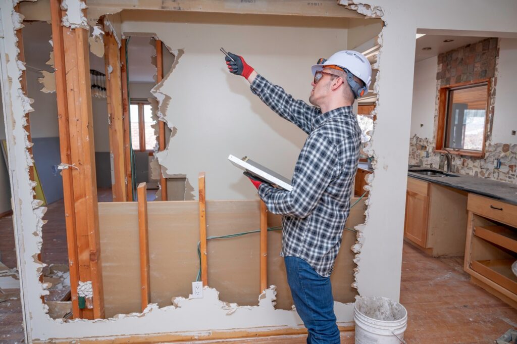 Insurance inspector assessing accidental wall damage during home renovation in New York property