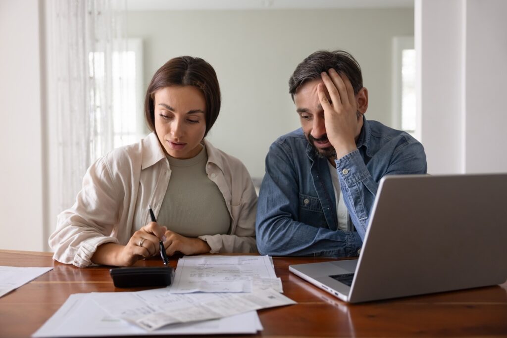 Stressed couple reviewing underpaid insurance claim documents at home in New York