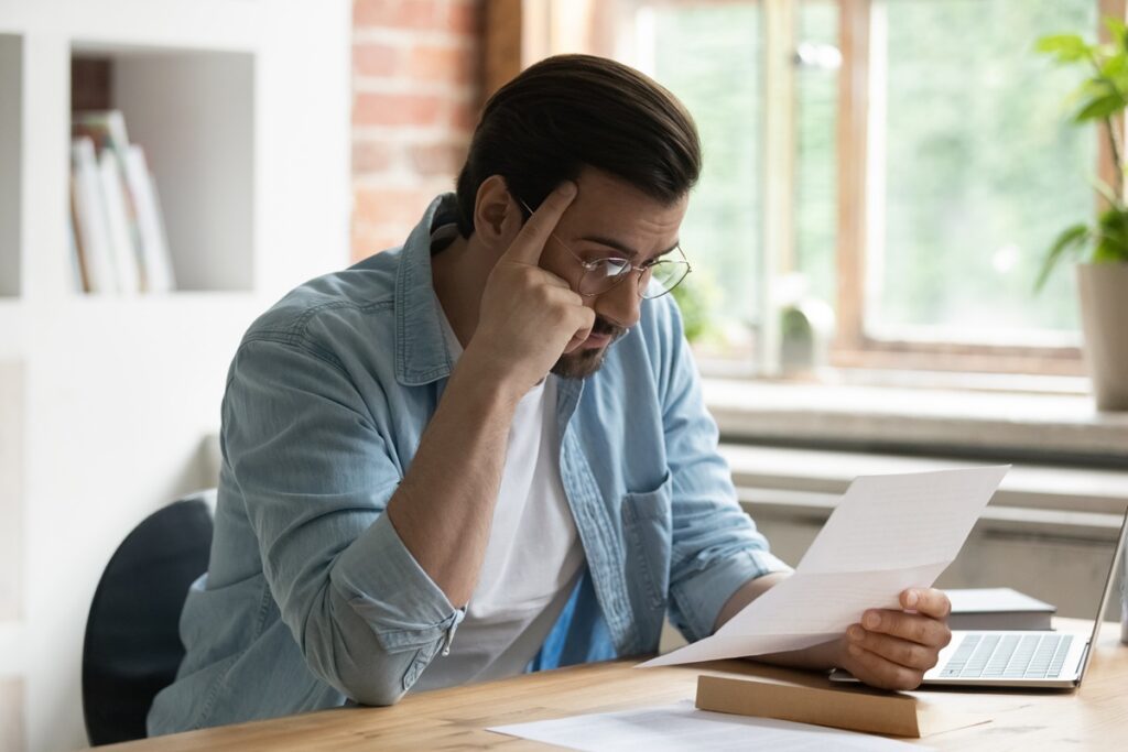 Stressed homeowner reading insurance denial letter representing bad faith insurance claim handling in New York