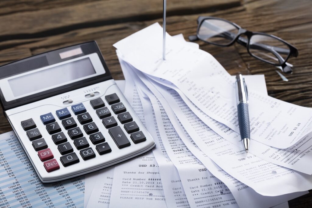 Calculator and a stack of receipts prepared as documentation for an insurance claim appeal.