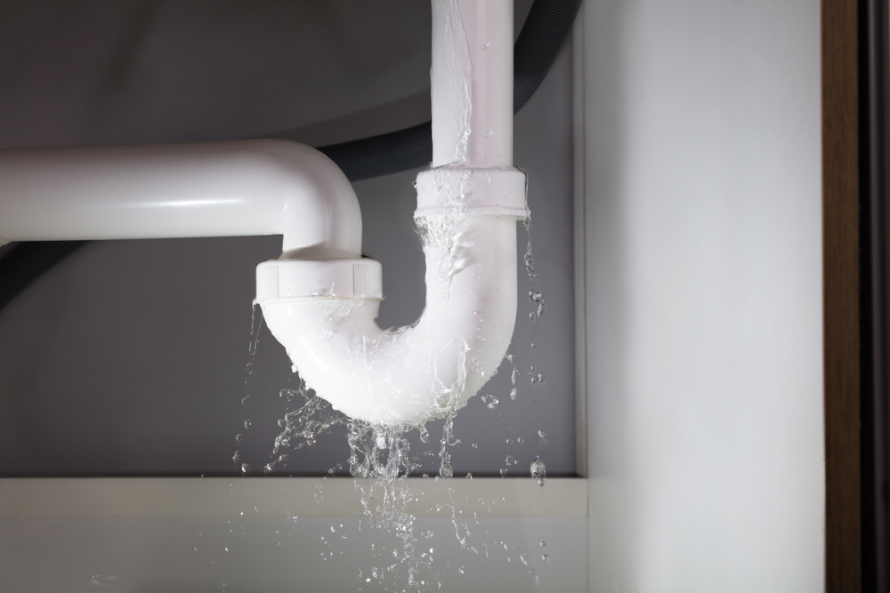 Burst pipe leaking water under sink representing water damage insurance claim in Connecticut