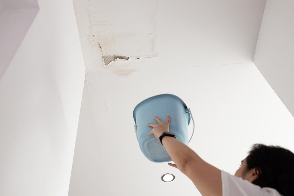 Homeowner catching water from leaking roof representing water damage insurance claim in New York